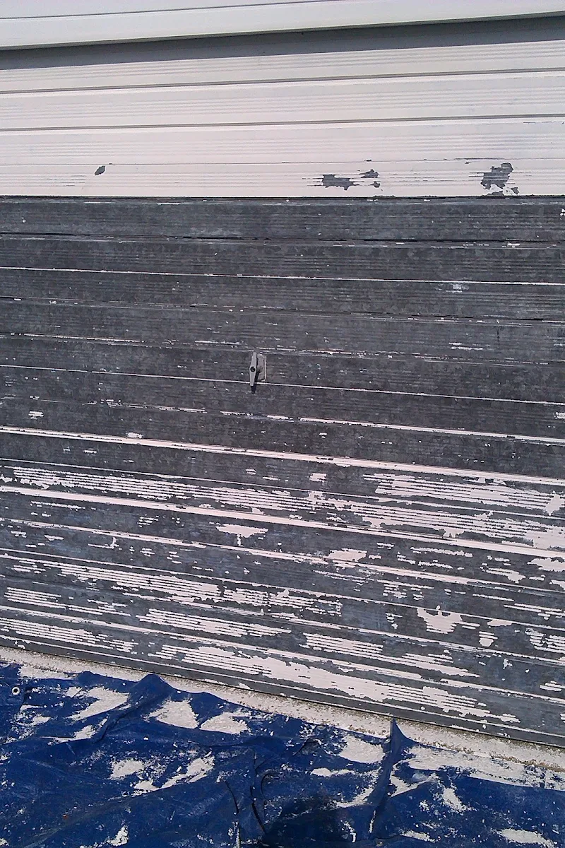 Weathered garage door with peeling paint before exterior repaint